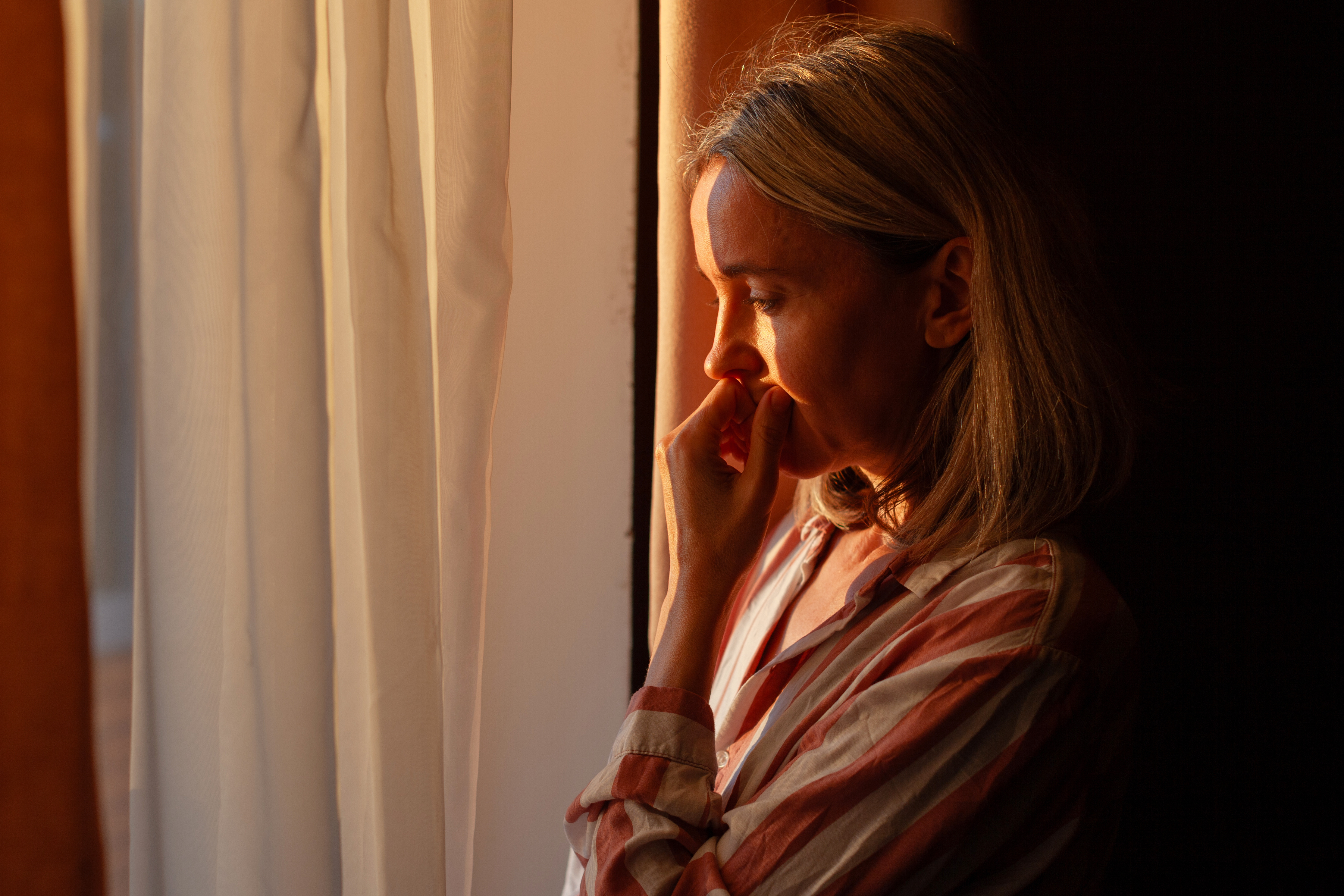 Woman in contemplative moment by window, representing the reflective journey of perimenopause